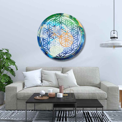 Moderner Wohnraum mit grauem Sofa, weißen Kissen und einem schwarzen Couchtisch vor einer weißen Wand, an der ein rundes, farbenfrohes Kunstwerk mit geometrischem Muster hängt.